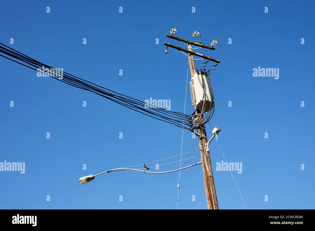 Pfosten/Lampenpfosten und Drähte gegen einen blauen Himmel Stockfoto