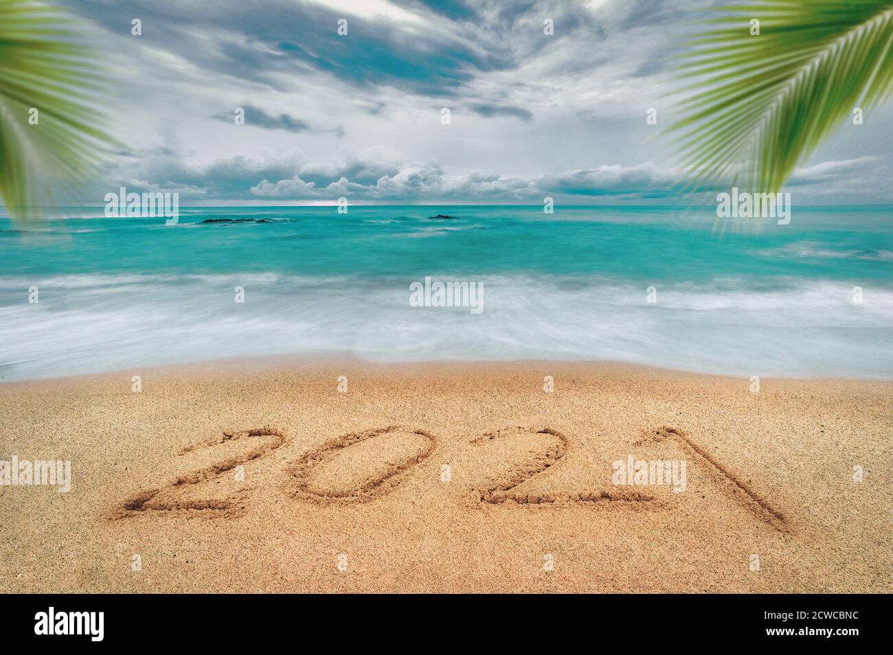 Frohes neues Jahr 2021, Schriftzug am Strand mit Welle und blauem Meer. Zahlen 2021 Jahr an der Küste, Neujahrs-Konzept. Stockfoto