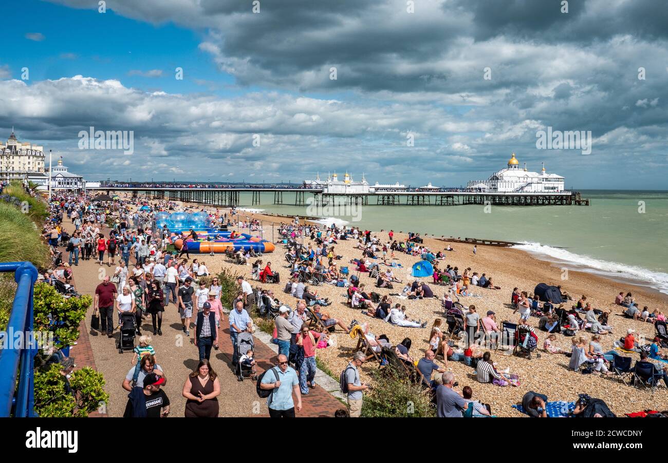 Eastbourne Meer und Pier. Eine geschäftige Strandszene auf dem Höhepunkt des englischen Sommers gefüllt mit Touristen, die das warme Wetter genießen. Stockfoto