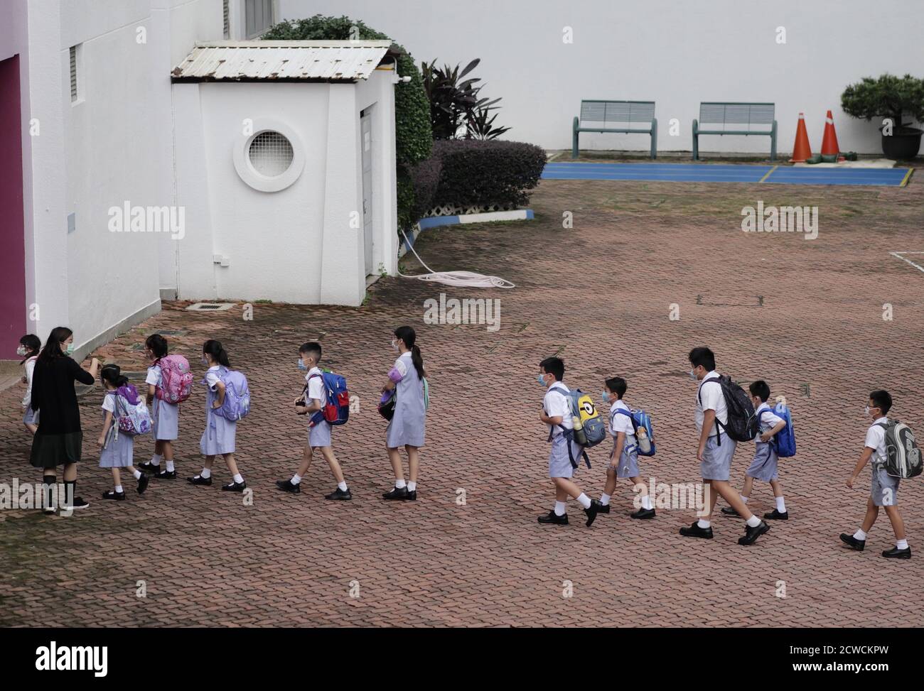 Hongkong, China. September 2020. Schüler stehen Schlange, um eine Grundschule in Hongkong, Südchina, zu betreten, 29. September 2020. Die Epidemie hat sich in Hongkong nach einer schnellen Reaktion auf die Epidemie und der starken Unterstützung durch die Zentralbehörden stark entspannt. Die sozialen Distanzierungsmaßnahmen wurden teilweise gelockert und das Leben der Menschen hat begonnen, sich wieder zu normalisieren. Alle Schüler kehrten am Dienstag in einer zweiphasigen Anordnung zu den Campus zurück, nachdem das persönliche Lernen vor etwa einer Woche für bestimmte Klassen verfügbar war. Quelle: Wang Shen/Xinhua/Alamy Live News Stockfoto