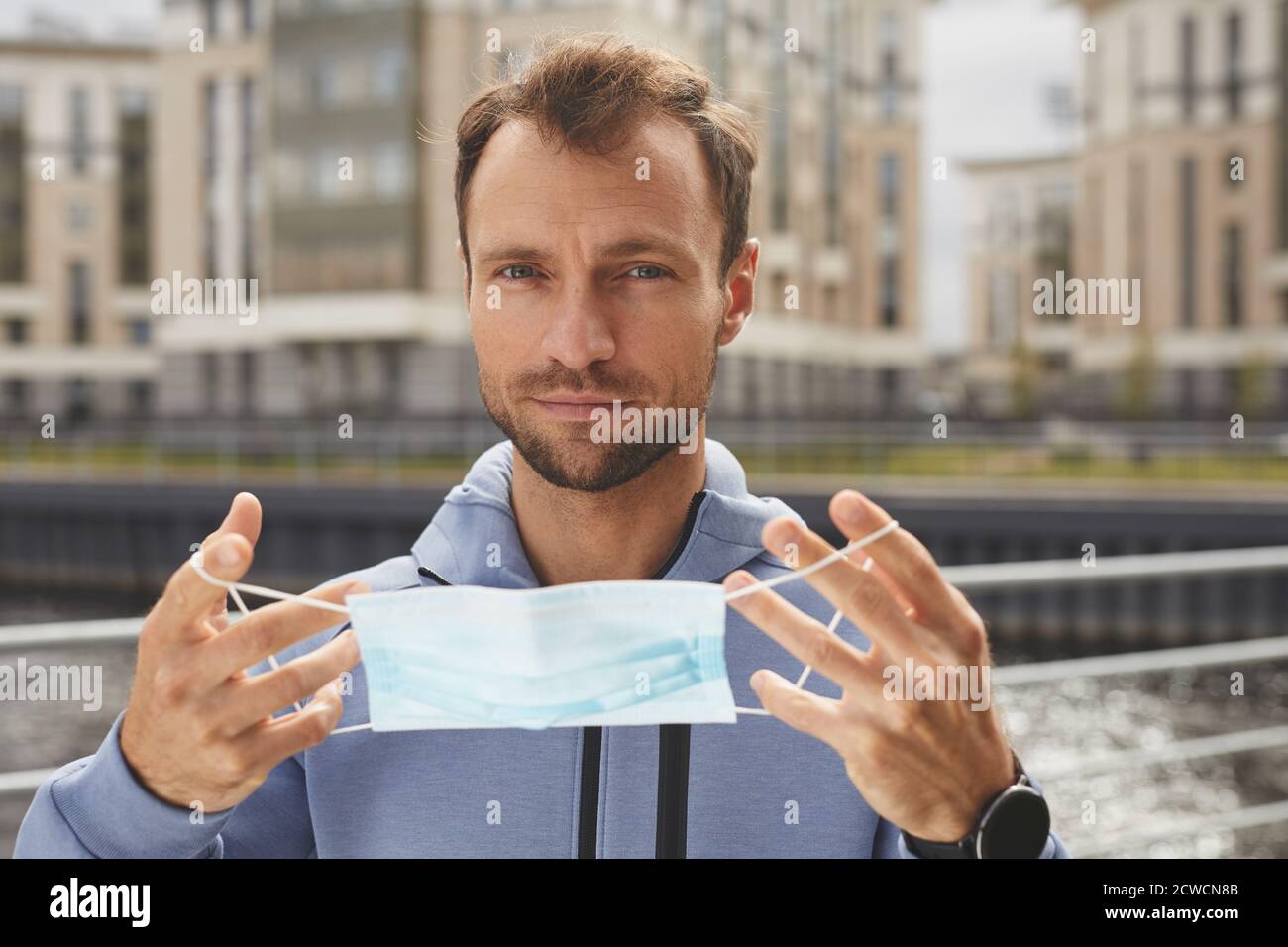Porträt eines jungen Mannes, der die Kamera betrachtet, während er Schutzkleidung trägt Maske steht im Freien Stockfoto
