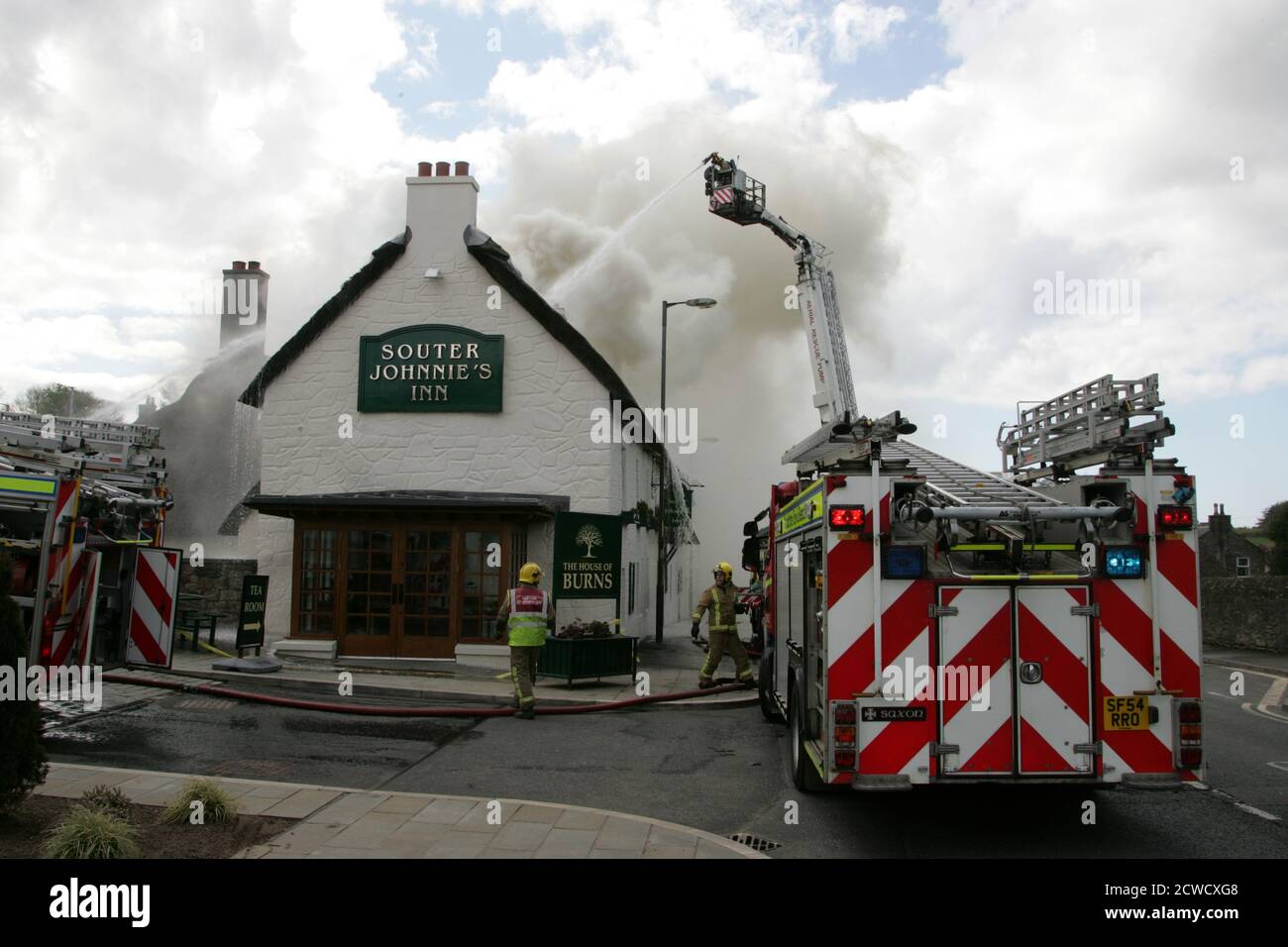 Kirkoswald, Ayrshire, Schottland, Großbritannien, 18. April 2012. Lokales Restaurant Souter Johnnies Inn fing Feuer in der Strohdachfläche, die schnell ergriffen und zerstörte das Gebäude.Feuerwehrleute auf einer Lufthals-Plattform gegen den Brand Stockfoto