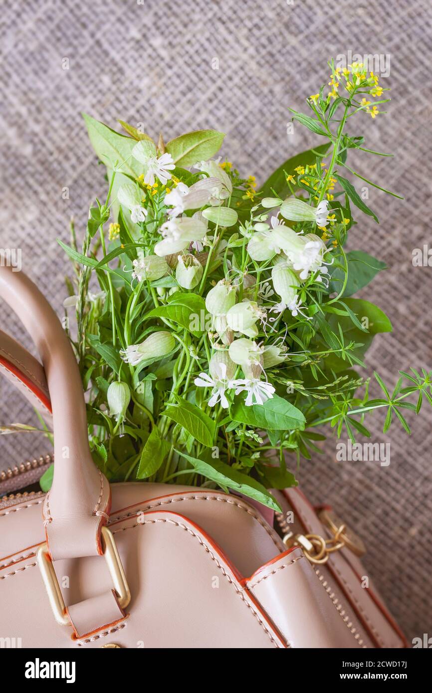 Handtasche mit Blumenstrauß auf Canva Hintergrund Stockfoto
