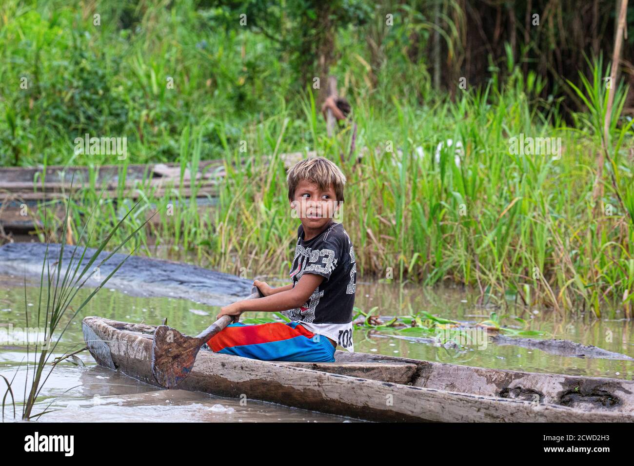 Der Junge paddelt sein Kanu auf dem Oxbow See Atun Poza, Iquitos, Peru. Stockfoto