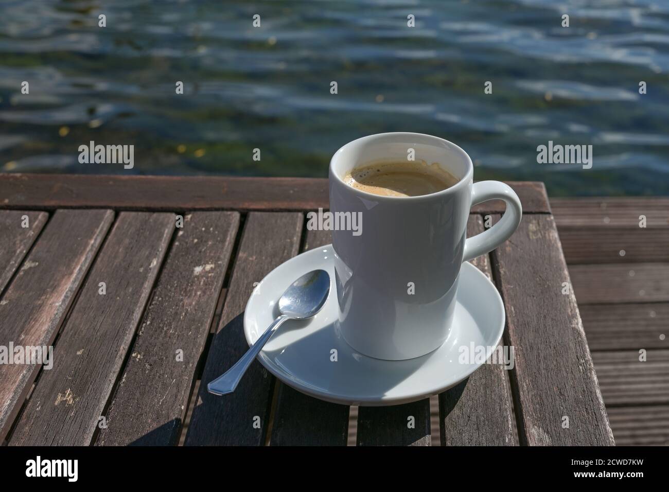 Große Tasse mit Kaffee auf einem Holztisch direkt am Wasser in einem Outdoor-Café, Kopierraum, ausgewählter Fokus, enge Schärfentiefe Stockfoto