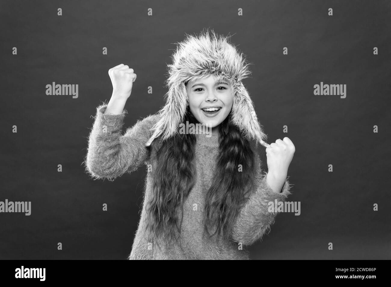 Fashion Model verschleiß Pelzmütze roten Hintergrund. warmen Kid Mode. saisonale Gesundheitsversorgung. Urlaub Aktivität im Freien. Happy kleines Mädchen in earflap hat. kleines Kind bereit für den Winter. bereit für Spaß. Stockfoto