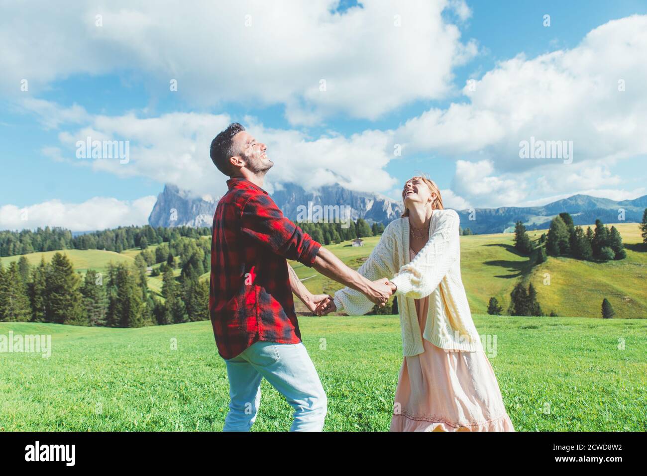 Glückliches Paar im Urlaub auf den italienischen dolomiten. Junger Mann und Frau spielen zusammen auf der grünen Wiese Stockfoto