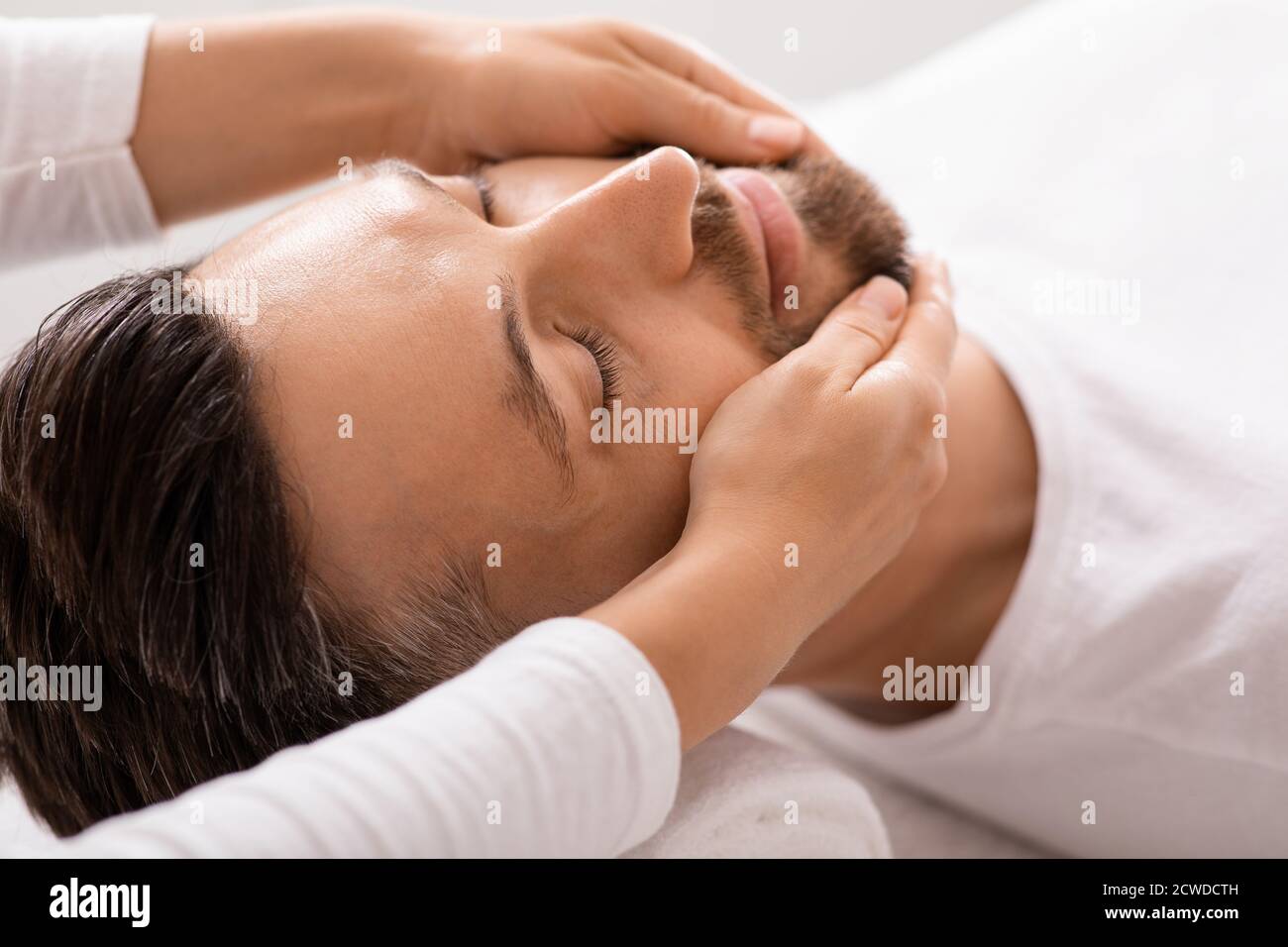 Nahaufnahme des Mannes, der im Spa eine heilende Gesichtsmassage bekommt Stockfoto