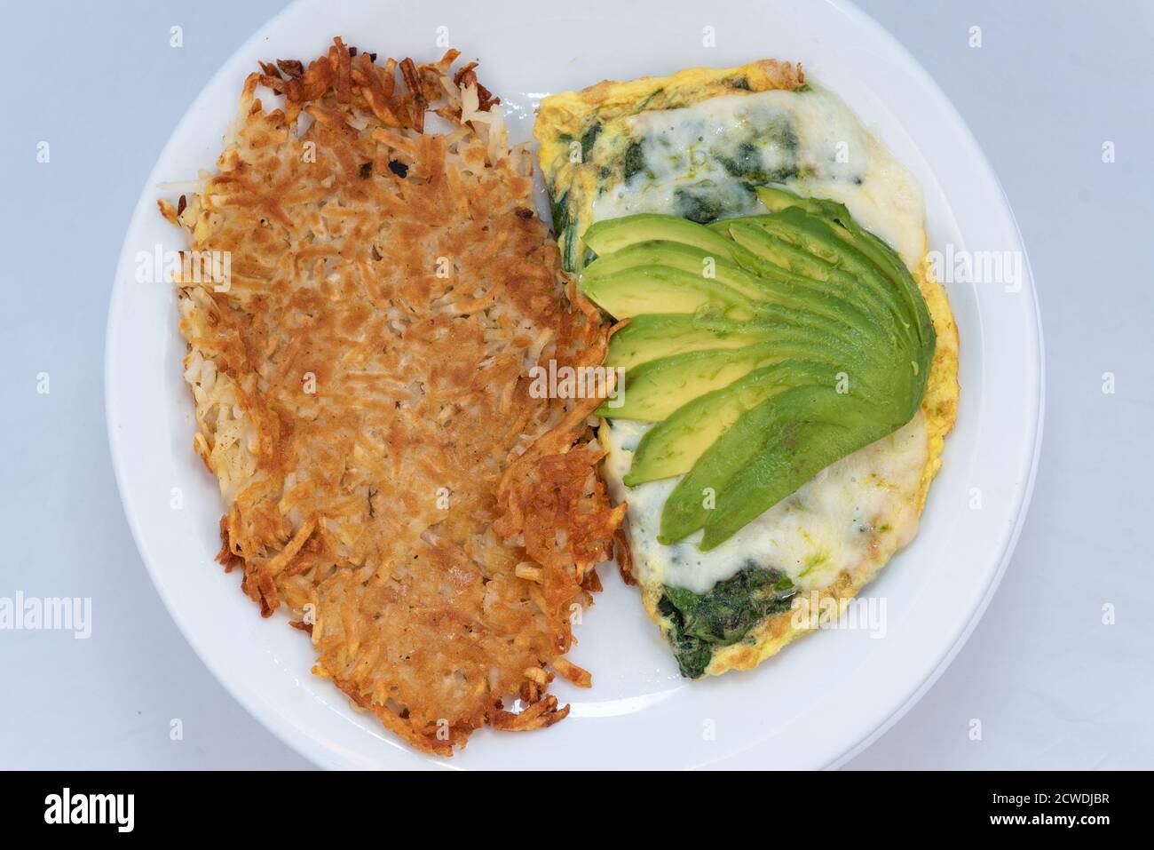 Blick von oben auf eine großzügige Mahlzeit mit einem herzhaften Avocado-Omelett mit Soße kombiniert mit Rösti. Stockfoto