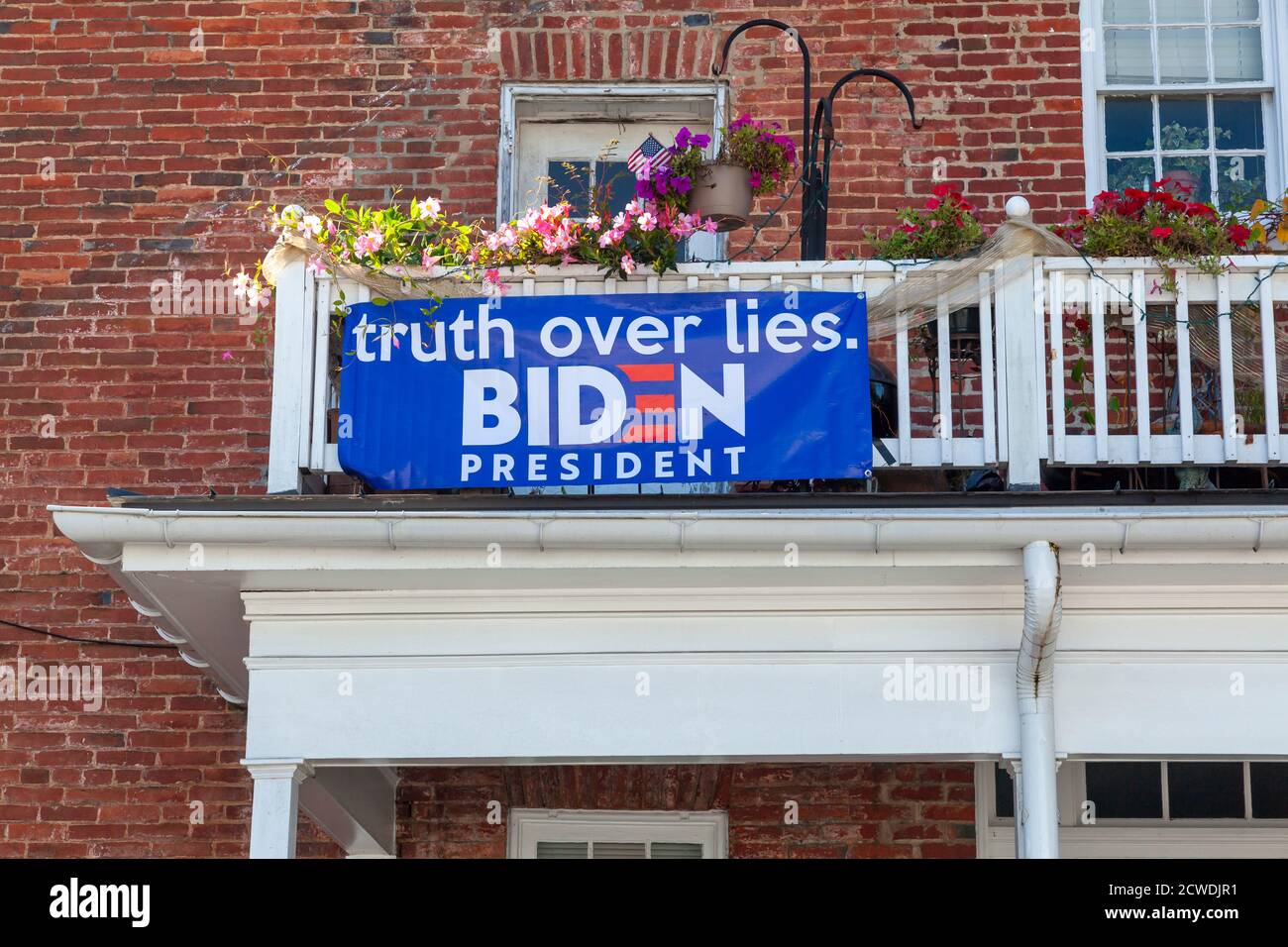 Berryville, VA, USA 09/27/2020: Ein blaues Biden for President Banner ist an den Holzgeländern des Balkons im zweiten Stock an einem alten Backsteinhaus befestigt Stockfoto