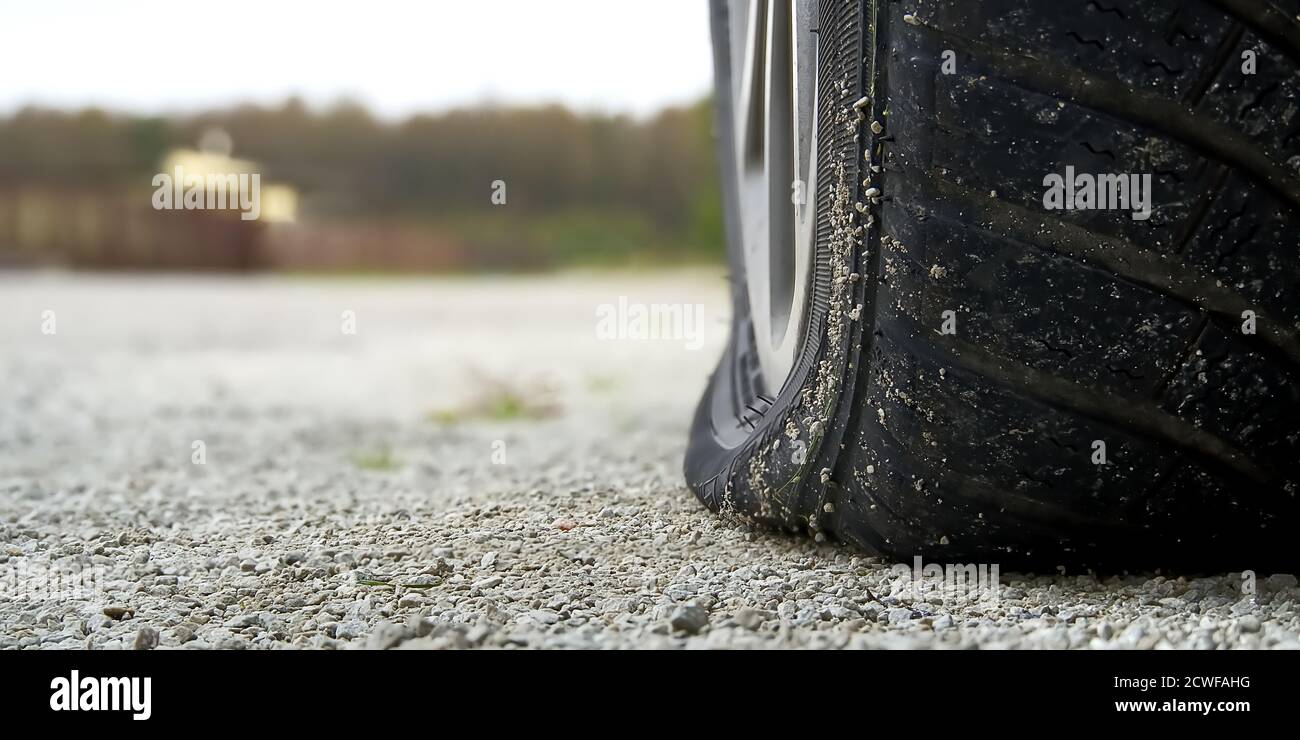Nahaufnahme des flachen Hinterreifens am Fahrzeug. Das rechte hintere zerbrochene Weel. Beschädigte Hinterräder auf dem Parkplatz. Stockfoto