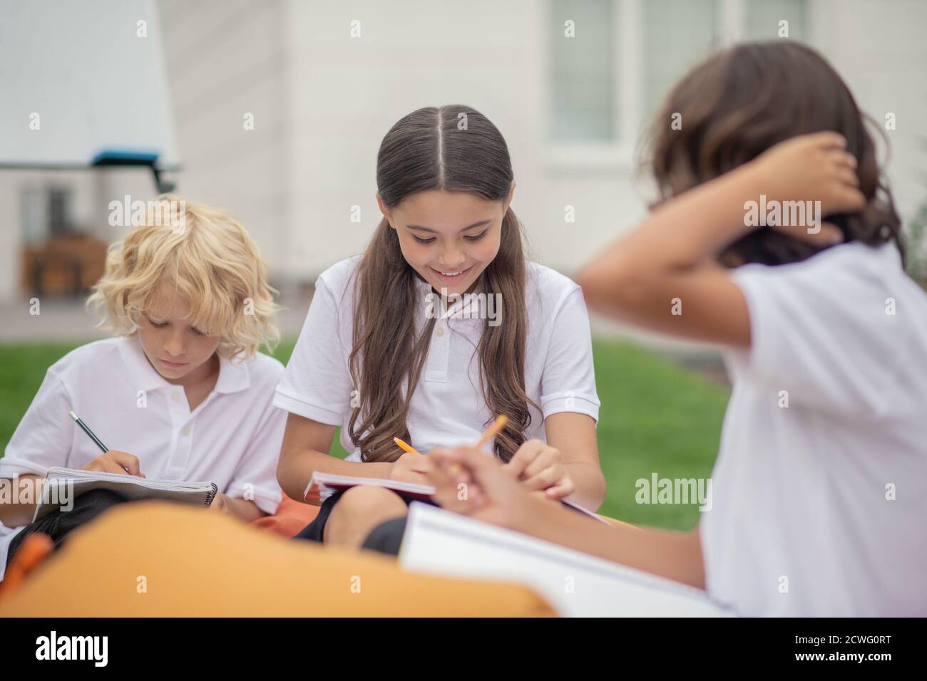 Kinder in weißen Hemden sitzen und studieren zusammen Stockfoto