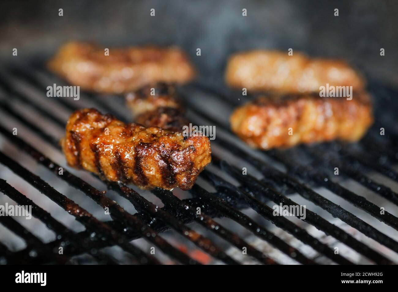 Geringe Schärfentiefe (selektiver Fokus) mit rumänischer traditioneller Mici (mititei), gegrillte Hackfleischrollen in zylindrischer Form auf dem Grill Stockfoto