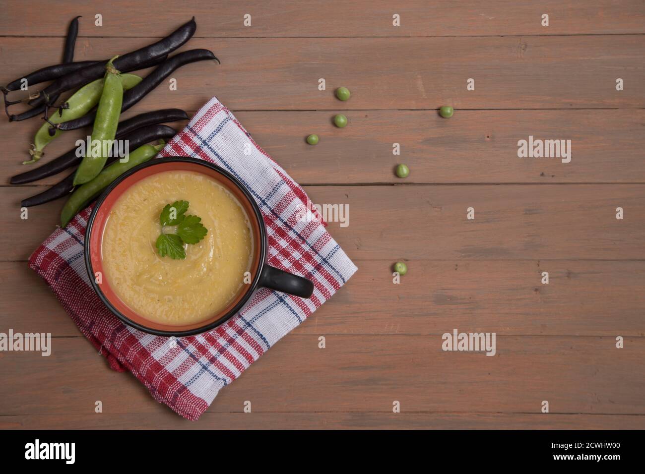 Suppenpüree aus Bohnen und Erbsen auf roter Serviette und braunem Holzhintergrund. Horizontale Ausrichtung. Platz für einen Kopierbereich Stockfoto