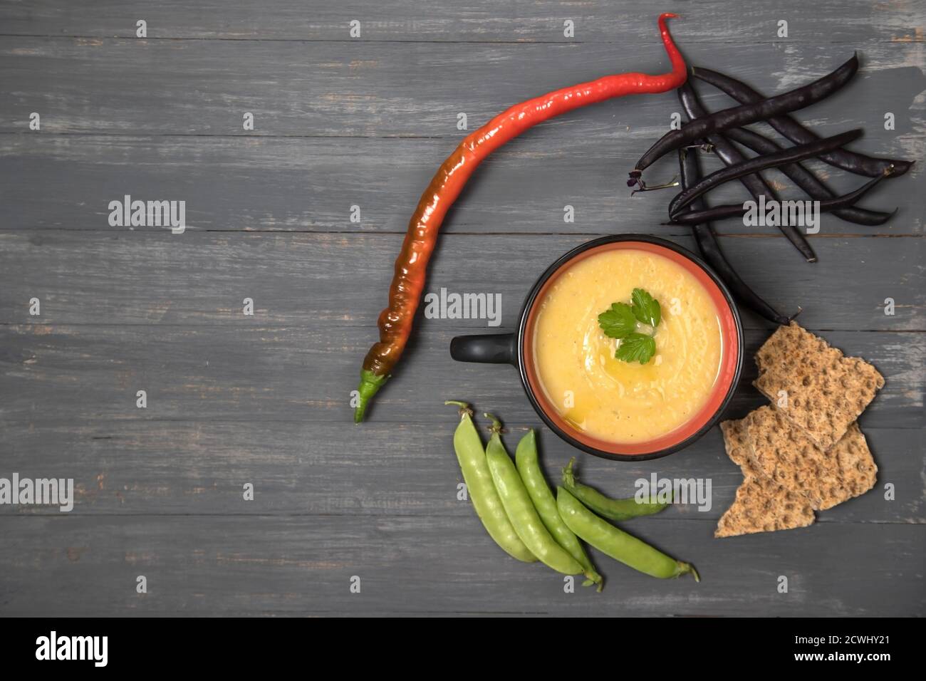 Tasse mit Suppenpürierten Bohnen und Erbsen auf dunklem Holzhintergrund mit Kräckern aus Getreide. Platz für einen Kopierbereich Stockfoto
