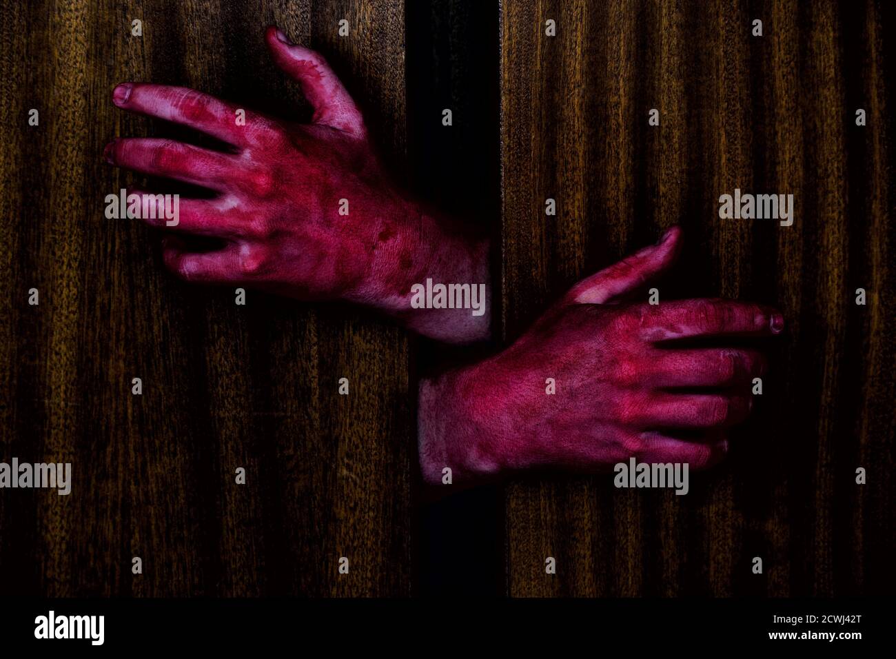 Zwei blutige Hände versuchen, aus einem dunklen Schrank zu kommen. Stockfoto