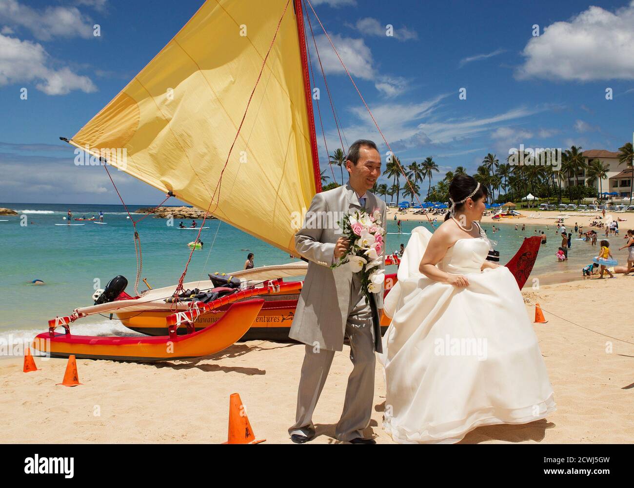 Ein japanisches Ehepaar geht vorbei Segelkanu am Strand nach der Einnahme  von Hochzeitsfotos als zwei Hurrikane Ansatz die Hawaii-Inseln in Honolulu,  Hawaii, 6. August 2014. Hawaiianer für einen Doppelschlag von ein paar