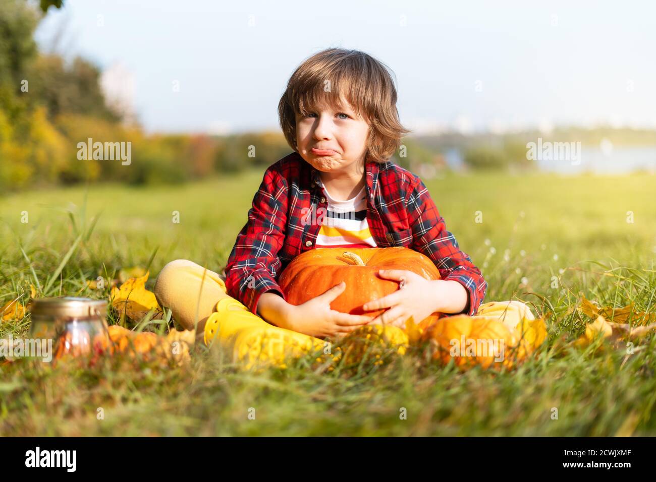 Niedlicher Junge spielen mit Kürbis im Herbstpark an Halloween. Kinder Trick or Treat. Spaß im Herbst. Verkleidetes Kind Stockfoto