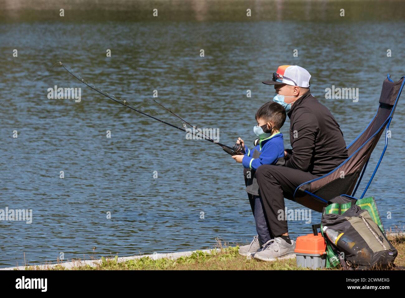 Ein asiatischer amerikanischer Vater und Sohn fischen gemeinsam am See in einem Park in Queens, New York City. Stockfoto