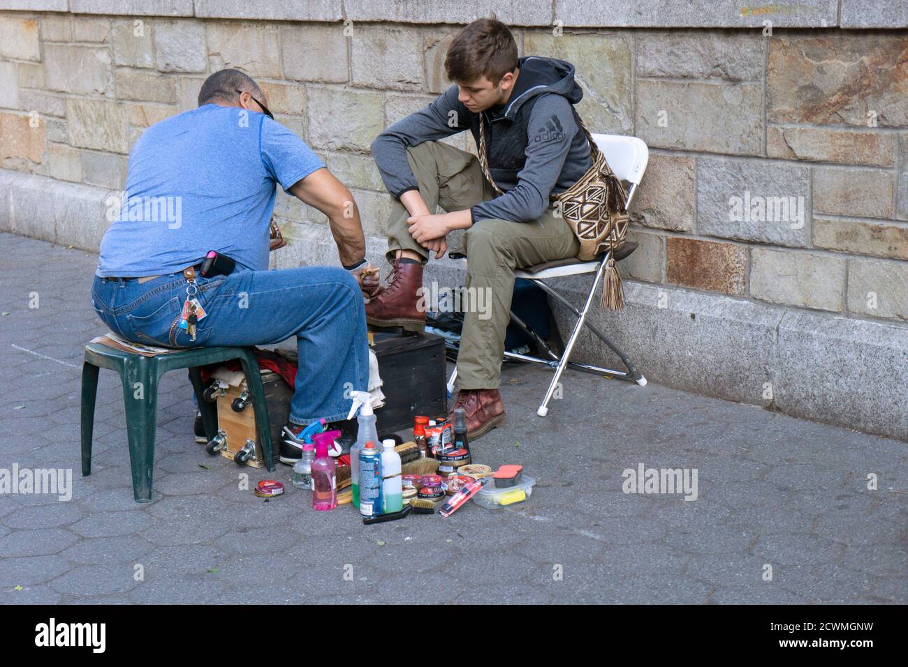 Ein junger Mann lässt seine Stiefel an einem altmodischen schuhputzstand im Union Square Park in Manhattan, New York City, erstrahlen. Stockfoto