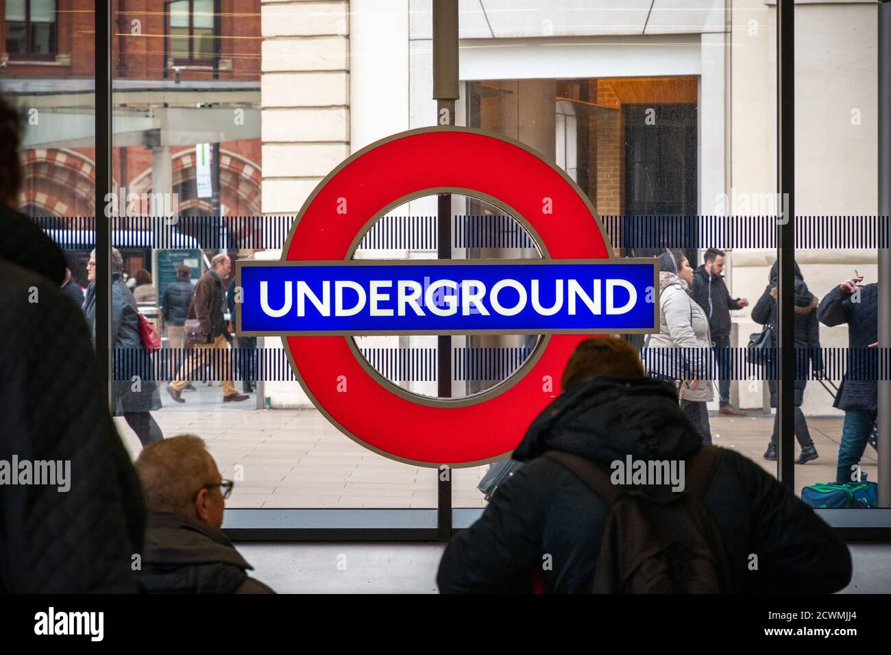 London, Großbritannien - 2. Februar 2020 - London U-Bahn-Schild an der U-Bahn-Station King's Cross St Pancras mit vorbeifahrenden Touristen Stockfoto