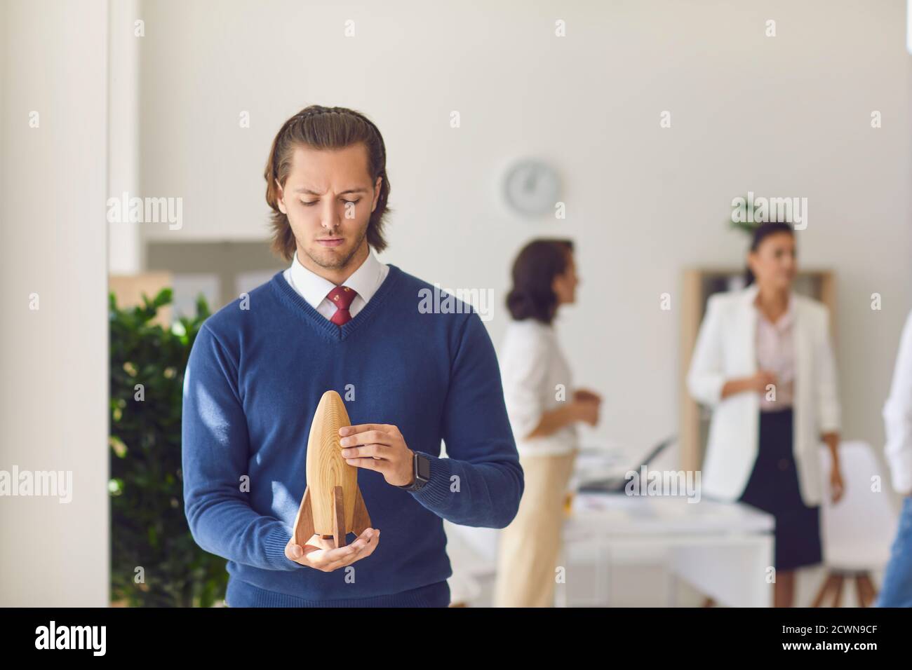 Büroangestellter hält Holzrakete in den Händen im Büro Stockfoto