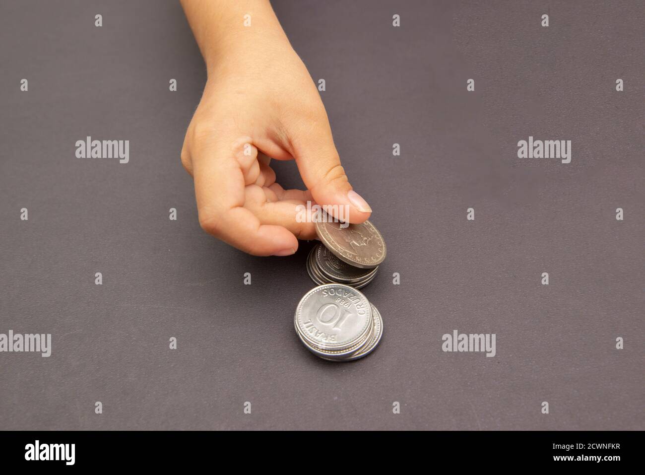 Zicklein Hände setzen goldene und silberne Münze auf Stapel von Münzen. Konzept des Sparens und Ausgabens von Geld. Zukünftige Investitionen. Langfristige Wirtschaftsplanung. Auswahl Stockfoto