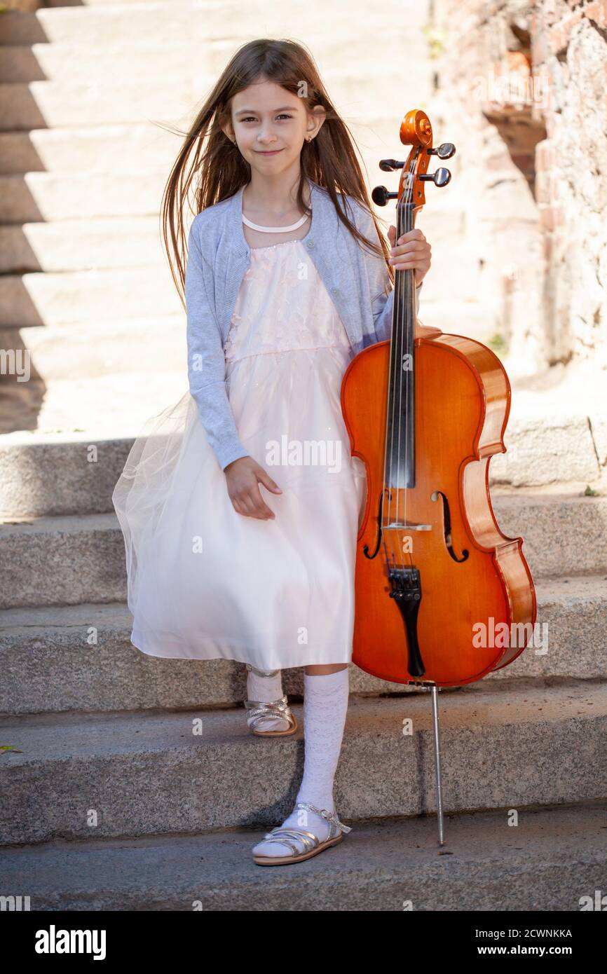 Schönes Mädchen mit einem Cello steht auf den Stufen Stockfoto