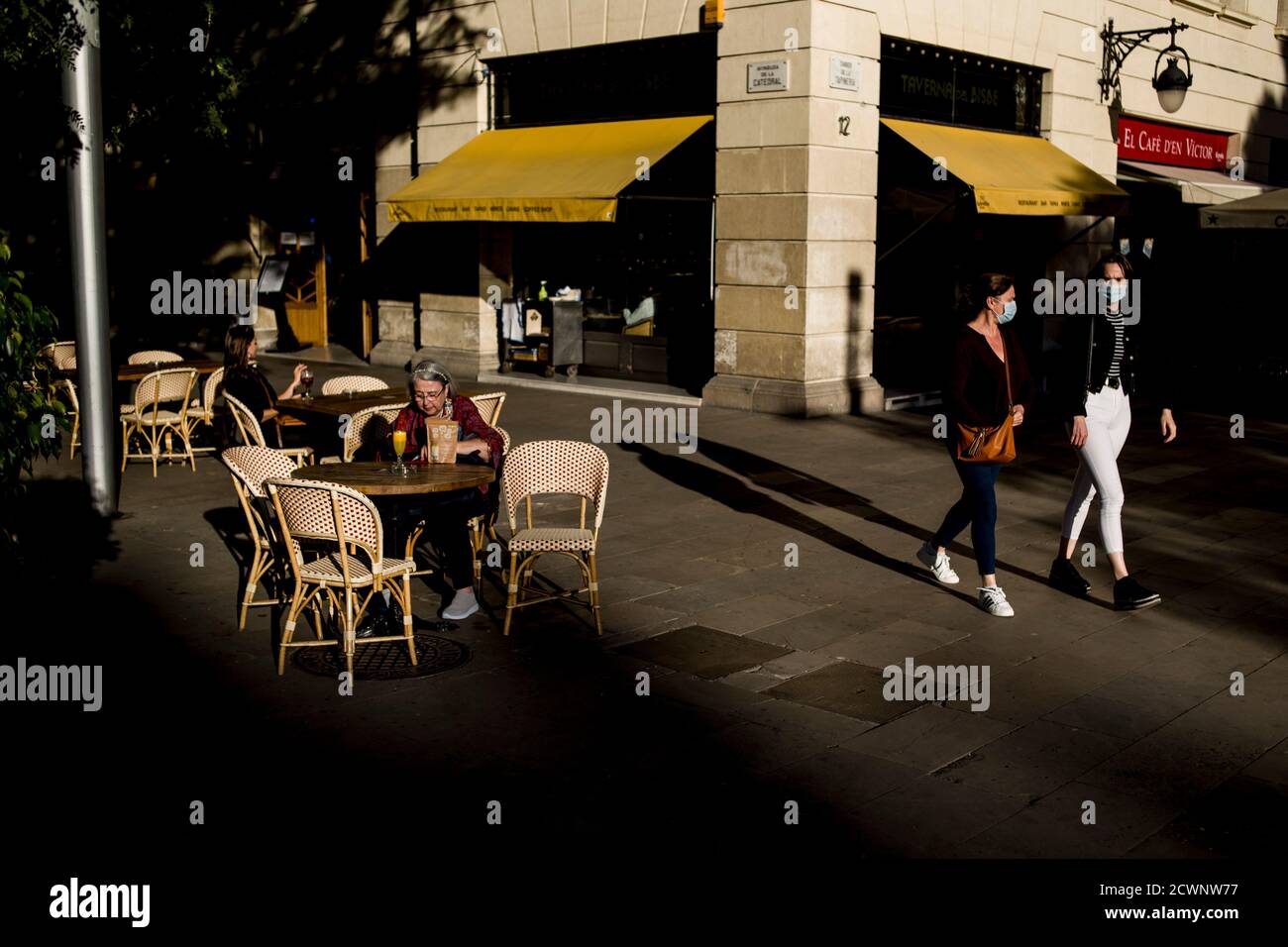 In der Innenstadt von Barcelona gehen Menschen, die Gesichtsmasken tragen, um die Ausbreitung des Coronavirus zu verhindern, an einer Barterrasse vorbei. Stockfoto