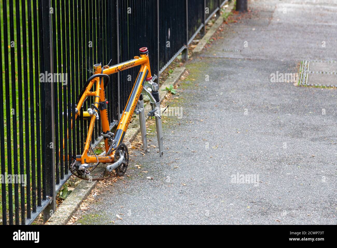 Ein Fahrrad an einem Metallzaun, der hatte gesperrt Seine Räder und Sattel gestohlen Stockfoto