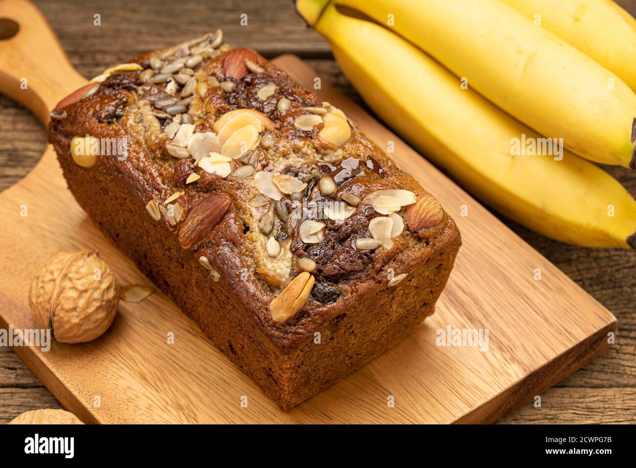 Nahaufnahme Bananenkuchen werden auf einem Holztablett auf einem Holztisch mit Bananen als Hintergrund platziert. Stockfoto