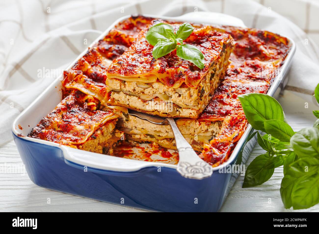 Gesunde fleischlose, milchfreie vegane Tofu-Lasagne mit Champignon-Pilzen, Tomatensauce, italienische Würze, serviert auf einer Backform mit frischen Kräutern Stockfoto