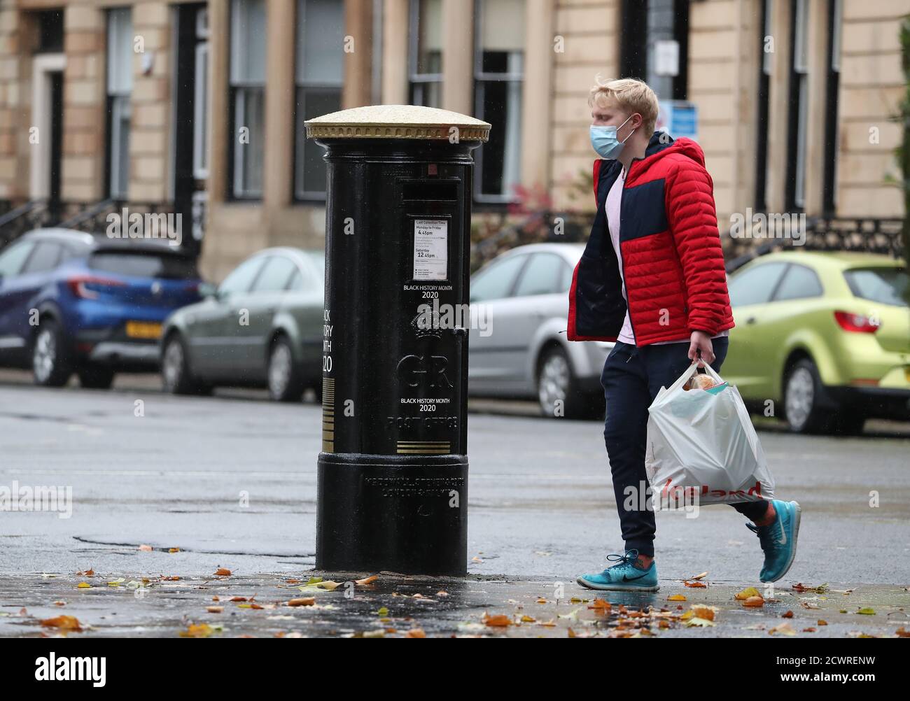 Ein Mitglied der Öffentlichkeit geht an einer schwarzen Briefbox vorbei, die ein Bild von Second Lieutenant Walter Tull zeigt, an der Byres Road, Glasgow, einer von vier Sonderpostboxen, die Royal Mail anlässlich des Black History Month enthüllt hat. Stockfoto