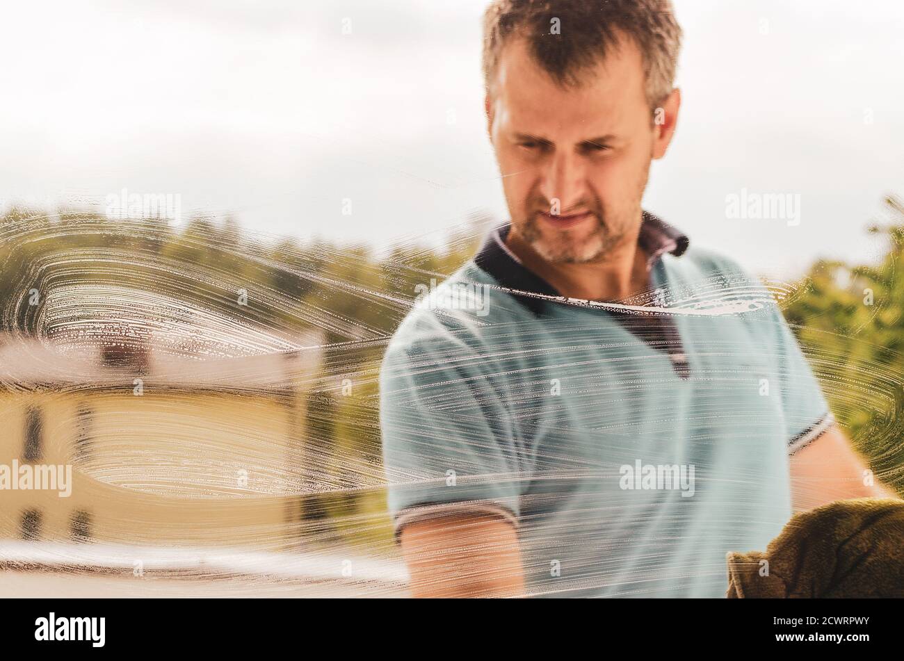 Ein Mann mittleren Alters putzte Fenster mit einem Lappen und Ein Fensterputzer Stockfoto