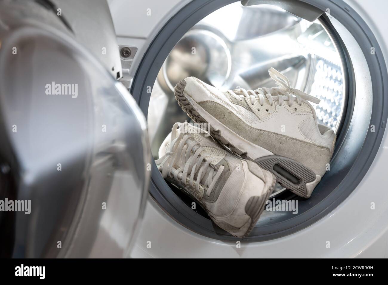Schuhhygiene - Paar schmutzige weiße Turnschuhe in der Waschmaschine Stockfoto