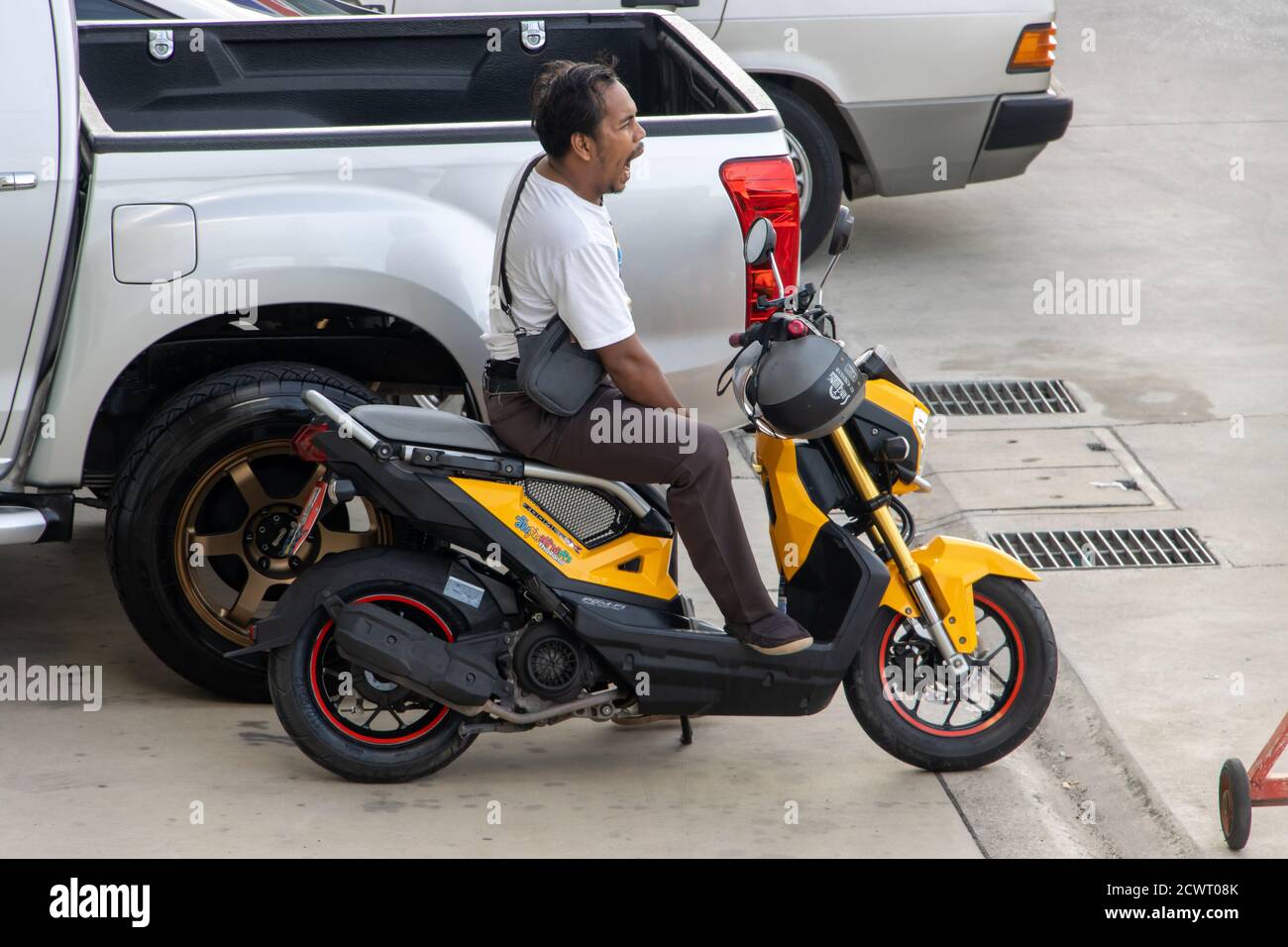 SAMUT PRAKAN, THAILAND, JUNI 15 2020, EIN Mann sitzt auf einem geparkten Motorrad und gähnt. Stockfoto