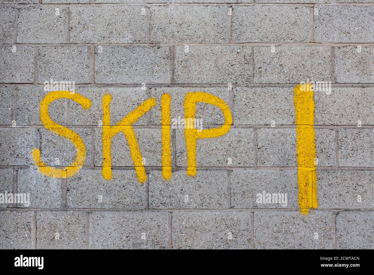 Das Wort SKIP graffisted auf einer Betonblockwand Stockfoto