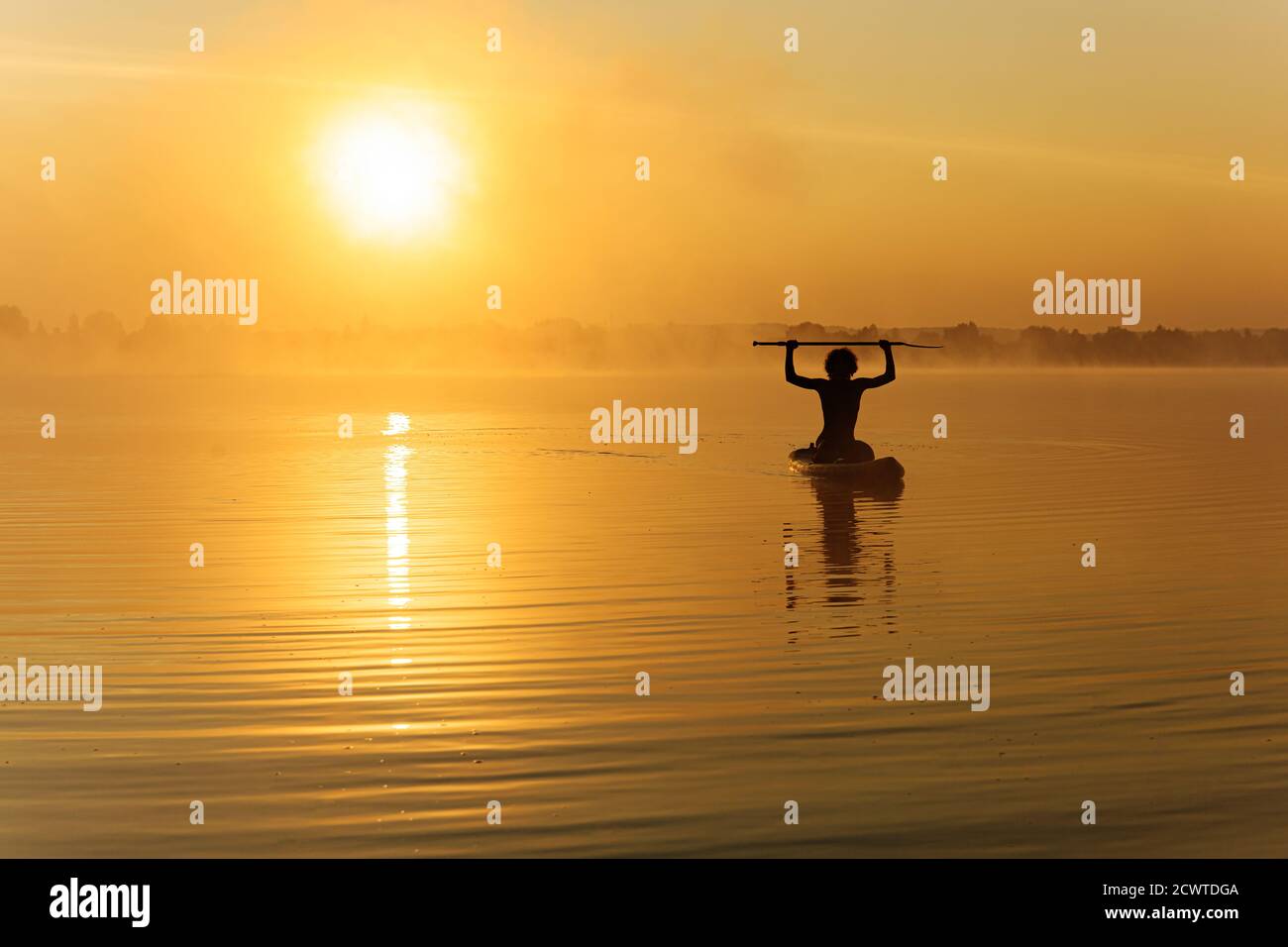Fröhlicher Mann, der morgens auf dem Paddle-Board trainiert Stockfoto