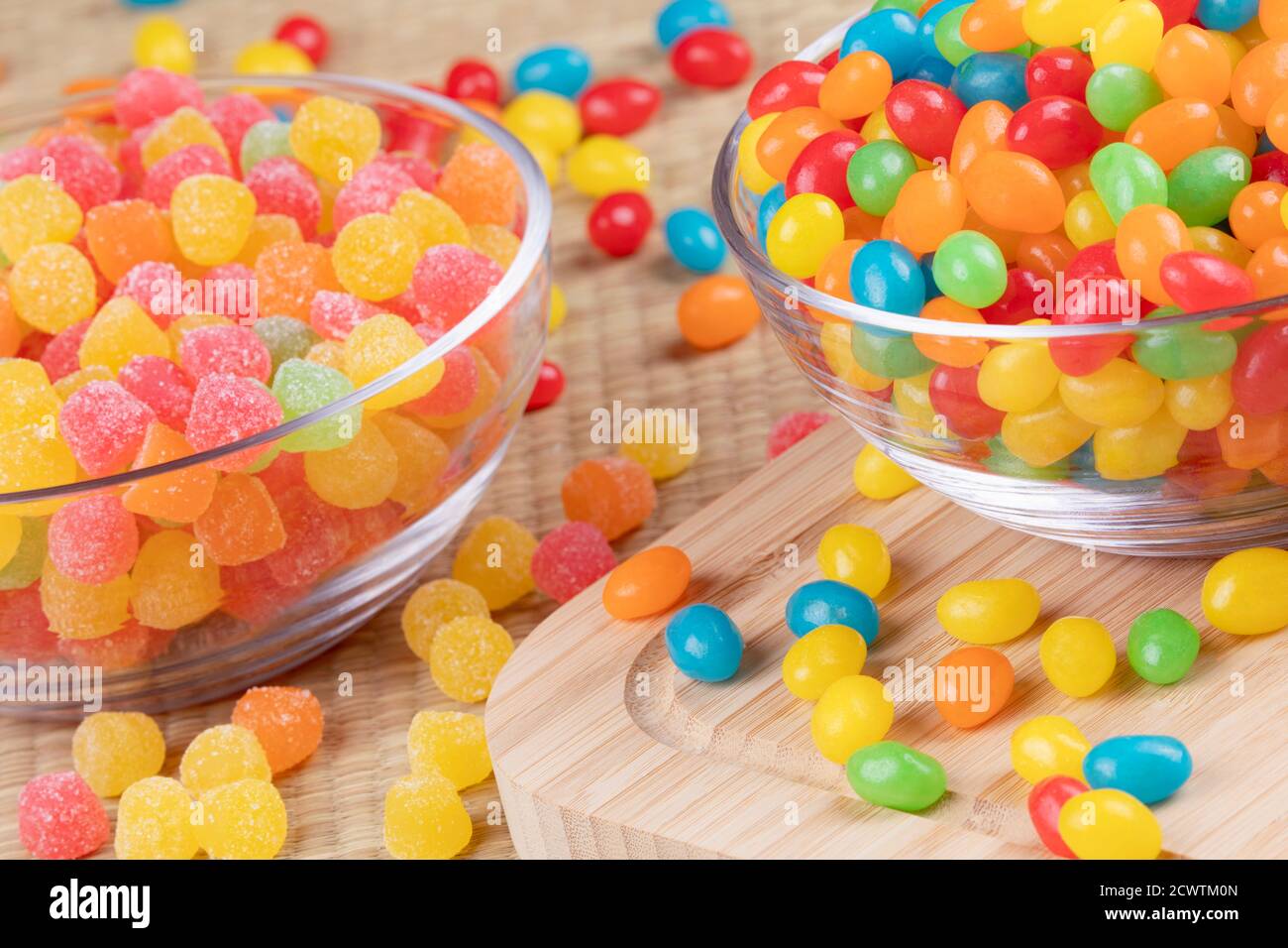 Köstliche Jelly-Bohnen und Fruchtgummitropfen in Glasschüsseln Auf einem hölzernen Hintergrund Stockfoto