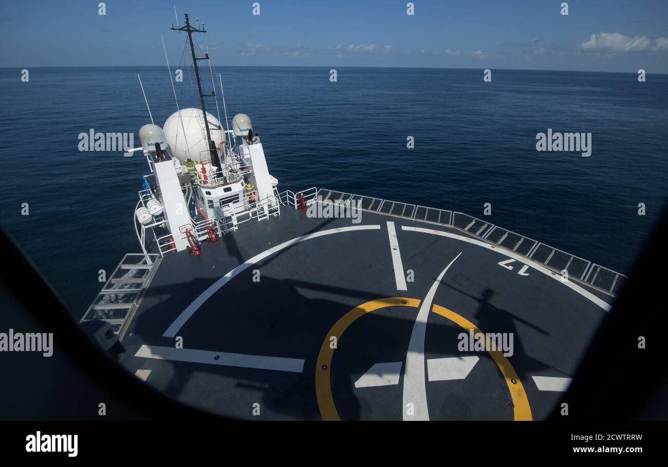 SpaceX Demo-2 die Landung des Hubschraubers mit den NASA-Astronauten Robert Behnken und Douglas Hurley zur Pensacola Naval Air Station wird auf dem SpaceX GO Navigator-Rückgewinnungsschiff als Silhouetten gesehen, nachdem das Duo in seiner Raumsonde SpaceX Crew Dragon Endeavour im Golf von Mexiko vor der Küste von Pensacola, Florida, landete, Sonntag, 2. August 2020. Der Demo-2-Testflug für das NASA Commercial Crew Programm war der erste, der Astronauten zur Internationalen Raumstation geliefert und an Bord eines kommerziell gebauten und betriebenen Raumschiffs sicher zur Erde zurückgebracht hat. Behnken und Hurley kehrten nach 64 Jahren zurück Stockfoto