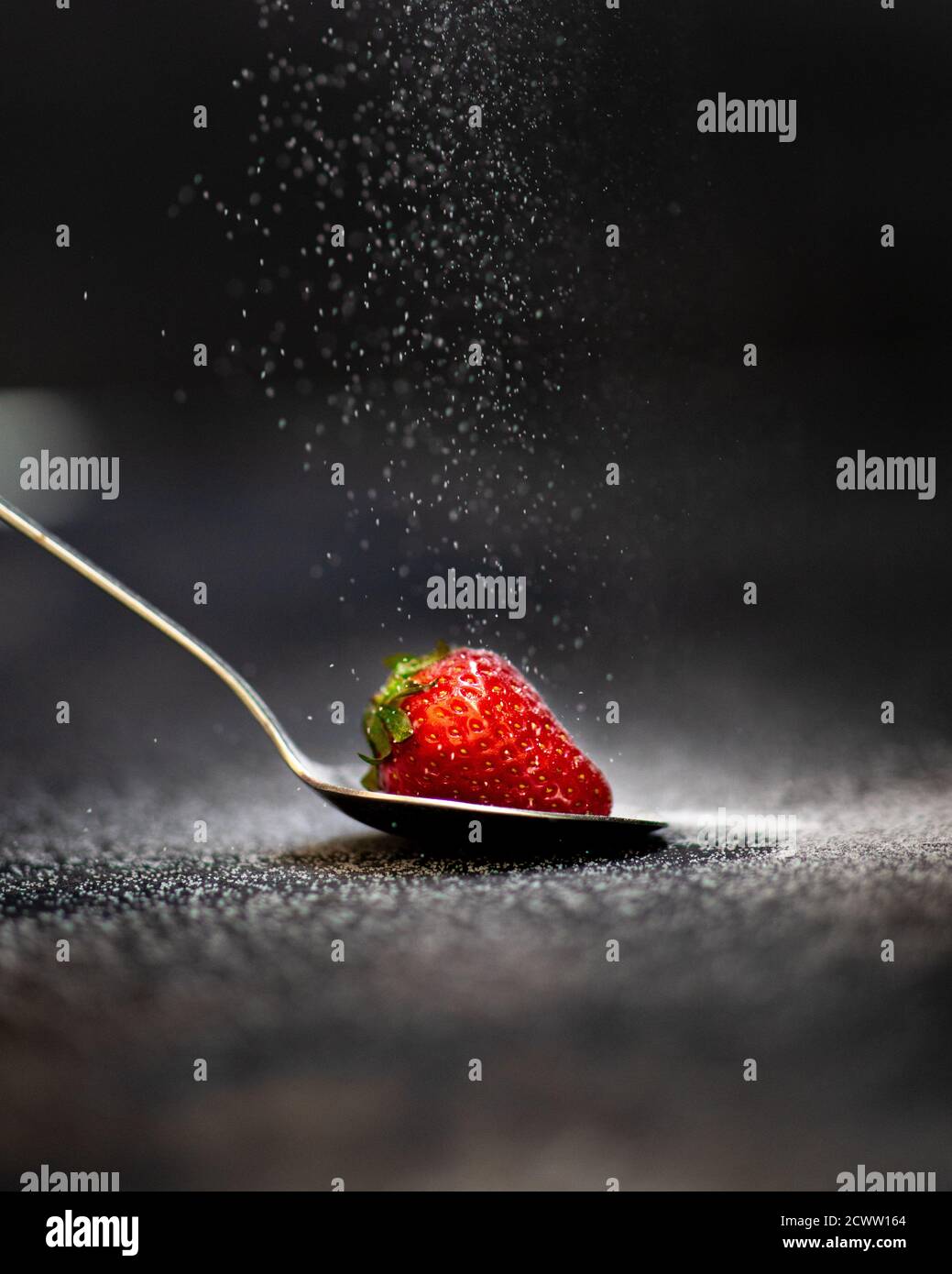 Eine Erdbeere auf einem Löffel mit Zucker bestreut Stockfoto