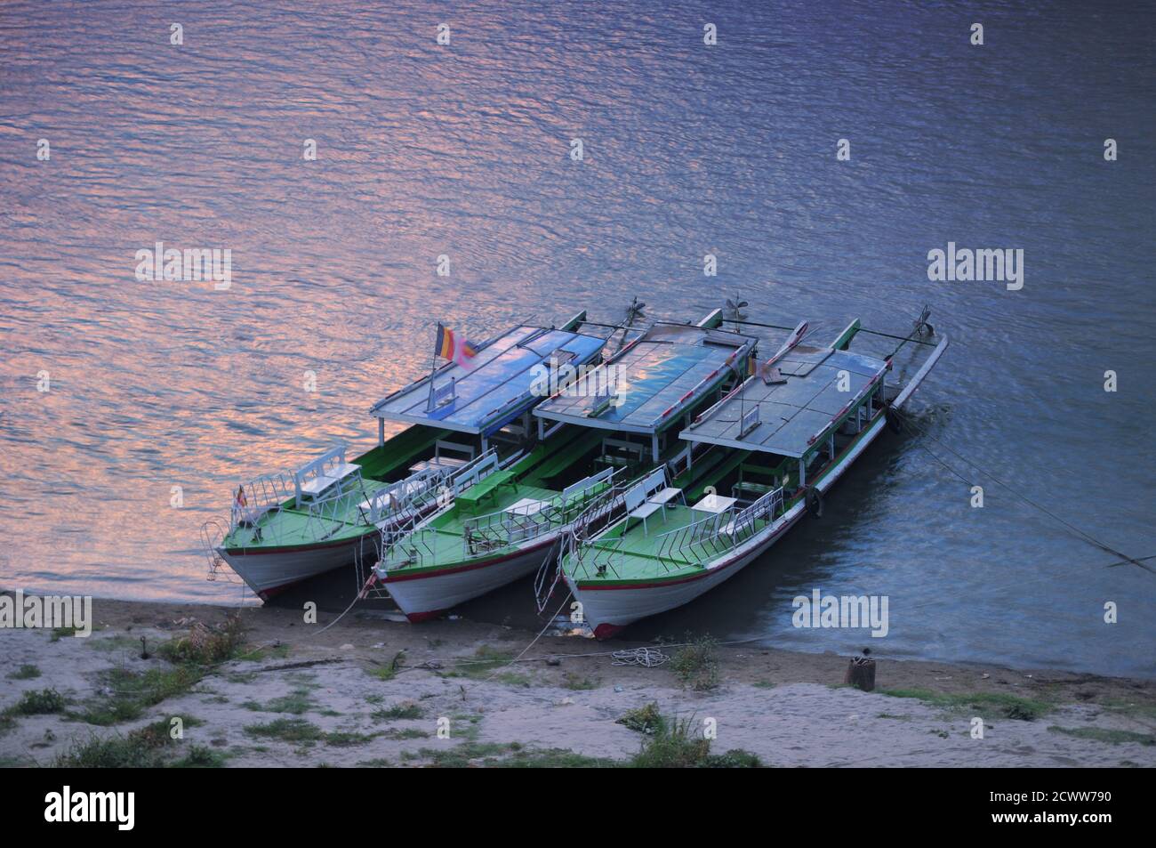 Drei traditionelle Holzboote, die am Flussufer geparkt sind Stockfoto