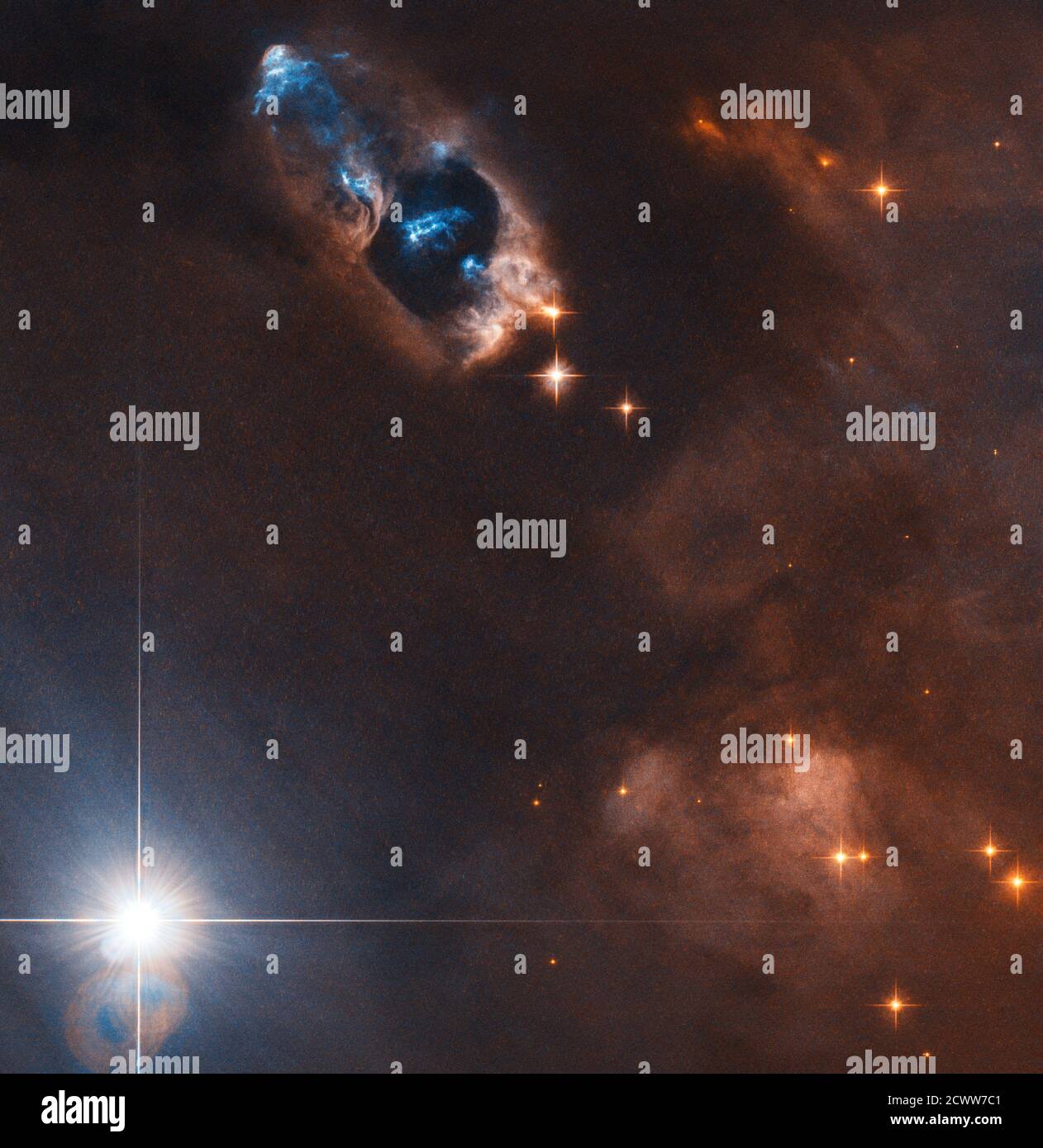 Hubble fängt Rauchkanone eines neugeborenen Sterns ein Sterne werden in dunklen Wolken aus Gas und Staub wie diesem geboren. Aber Sternentstehung ist ein energetischer Prozess, und neu gebildete Sterne können eine brillante Darstellung von Lichtern, Herbig-Haro-Objekte genannt, aussenden. Diese Objekte bilden sich, wenn vom neugeborenen Stern ausgespuckte Strahlen heißen Gases mit hoher Geschwindigkeit mit der umgebenden Materie kollidieren. In diesem Hubble-Weltraumteleskop-Bild können diese Objekte in der oberen Mitte als hellblaue Streifen gesehen werden, die sich von dem Stern, der sie mit 150,000 Meilen pro Stunde schuf, nach links oben wegbewegen. Stockfoto