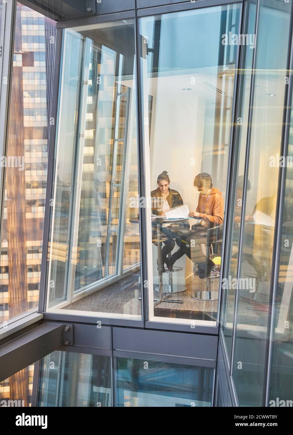 Geschäftsleute treffen sich an einem modernen Bürofenster in einem Hochhaus Stockfoto