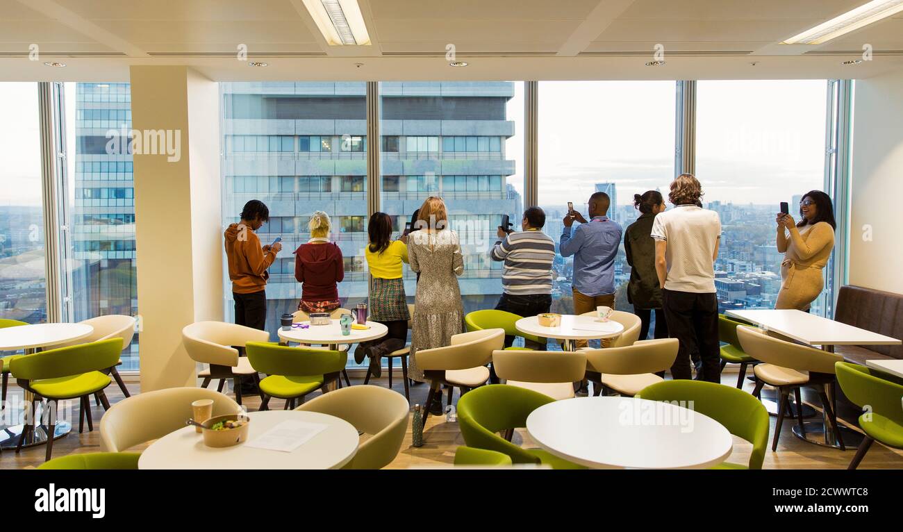 Geschäftsleute mit Kameratelefonen am Cafeteria-Hochhausfenster Stockfoto