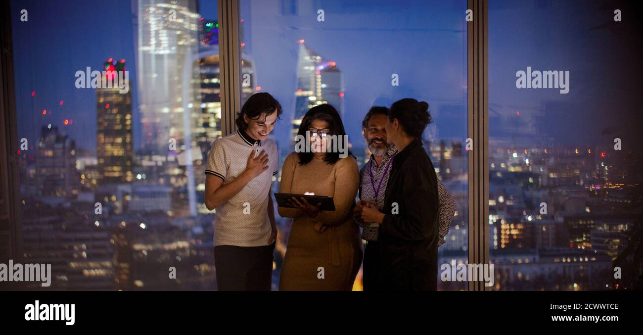 Geschäftsleute, die mit einem digitalen Tablet arbeiten, arbeiten spät am Hochhausfenster Stockfoto