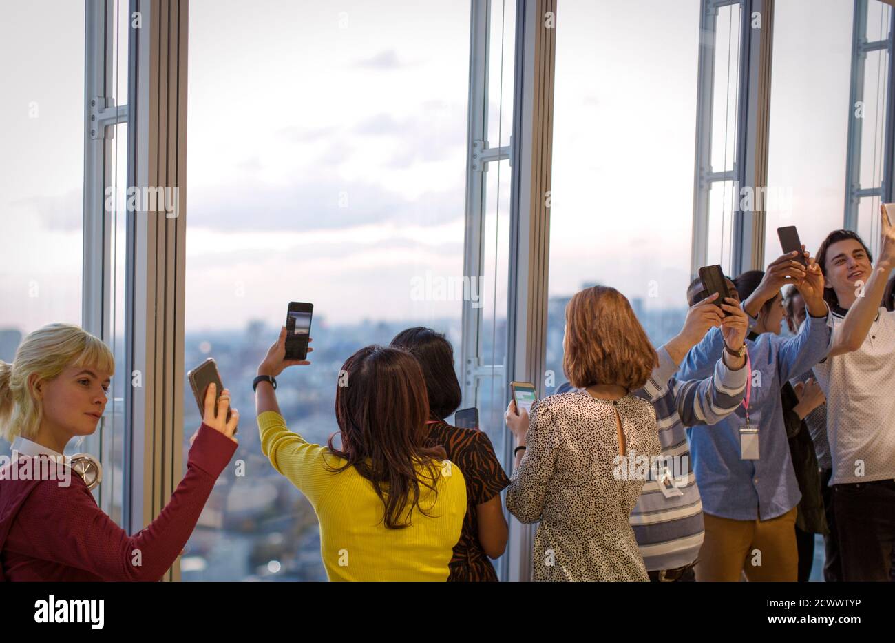 Geschäftsleute, die Selfies am Bürofenster im Hochhaus machen Stockfoto