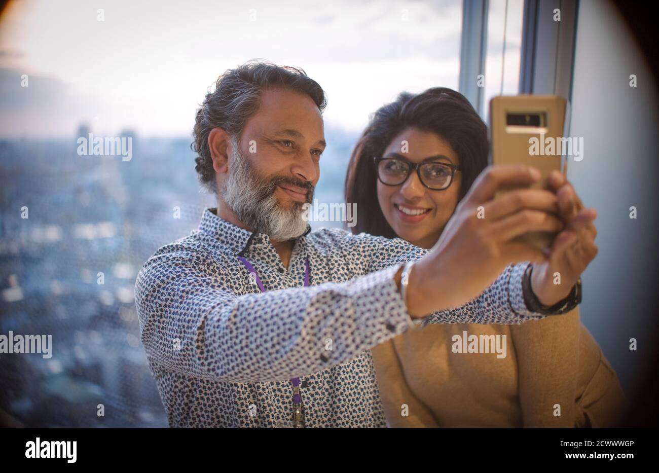 Geschäftsleute, die Selfie am Bürofenster im Hochhaus machen Stockfoto