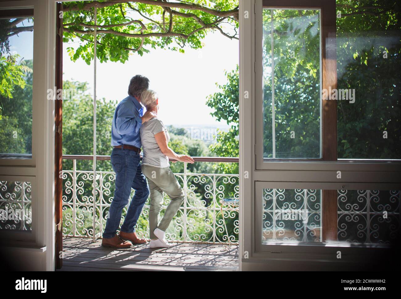 Liebevolles Seniorenpaar, das sich auf dem sonnigen Balkon entspannt Stockfoto