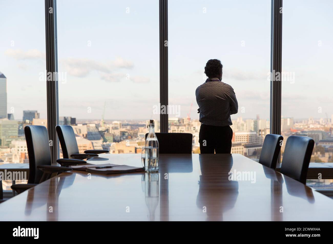 Ein nachdenklicher Geschäftsmann mit Blick auf das Fenster des städtischen Konferenzraums Stockfoto